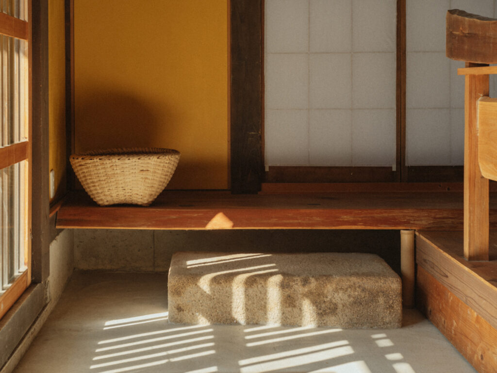 現在の住宅では見る機会も少なくなった沓脱石 (くぬぎいし) が印象的な玄関。奥の居間へと繋がる床板には、柔らかな印象の杉を採用した。
